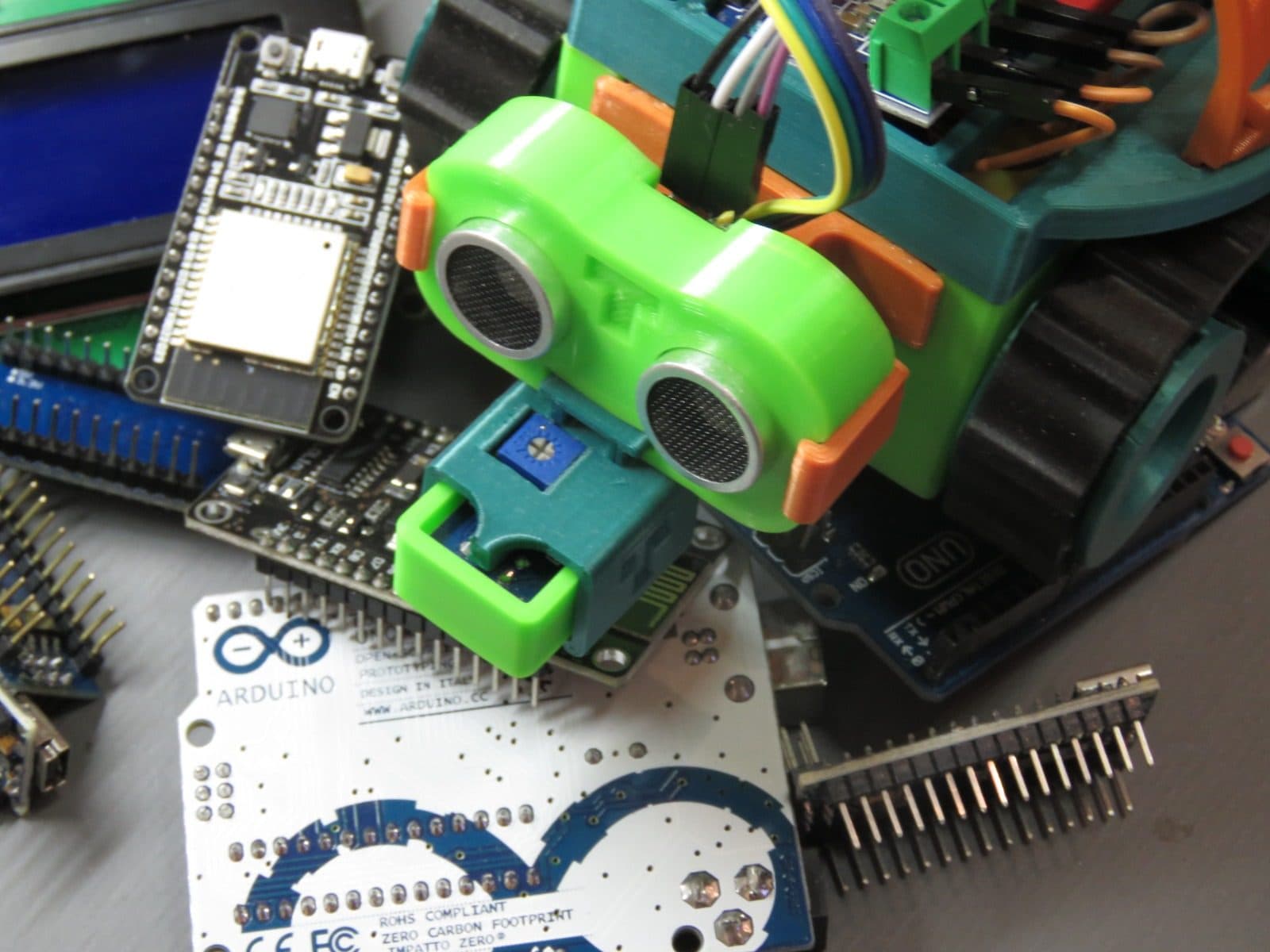 TurTle-T sobre a bancada, cercado de placas Arduino, ESP32 e barras de pinos.